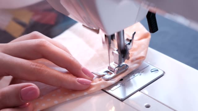 Woman sewing detail on the sewing machine. Close-up hand